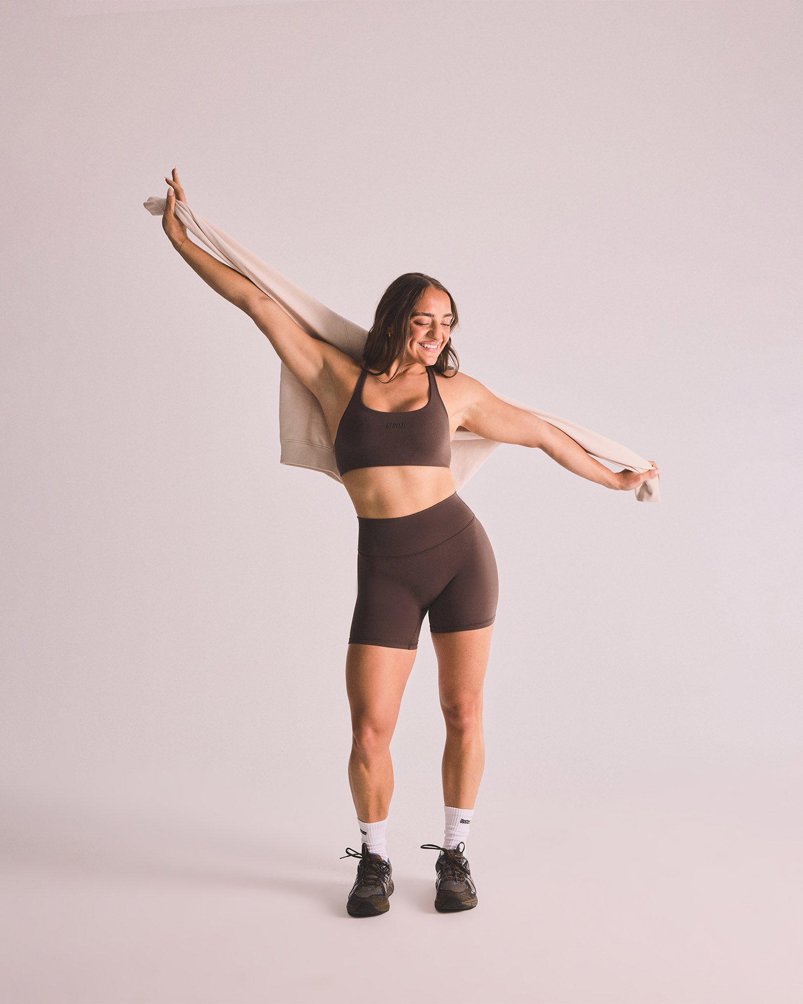 Woman in brown athletic wear posing against a plain background